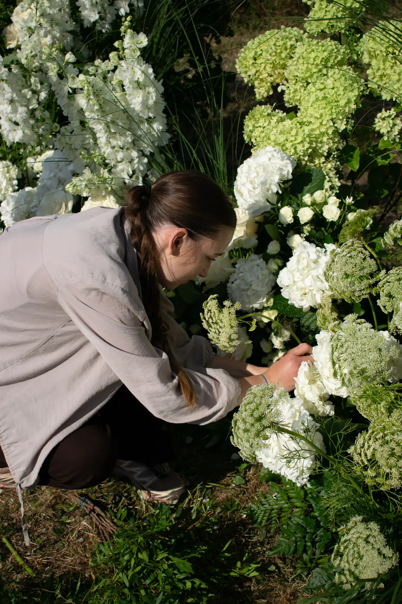 Floristka aranžuje bílé květiny ve venkovním prostoru