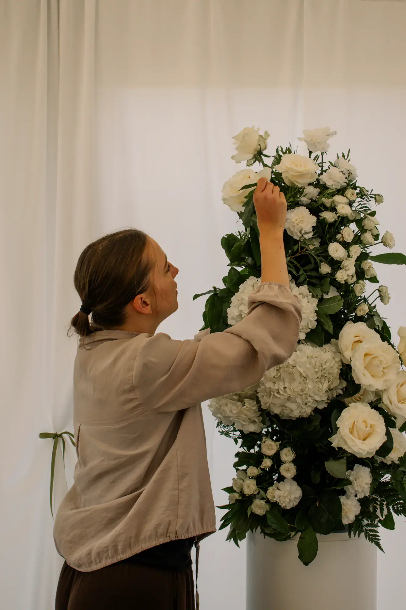 Floristka upevňuje květiny na svatební dekoraci